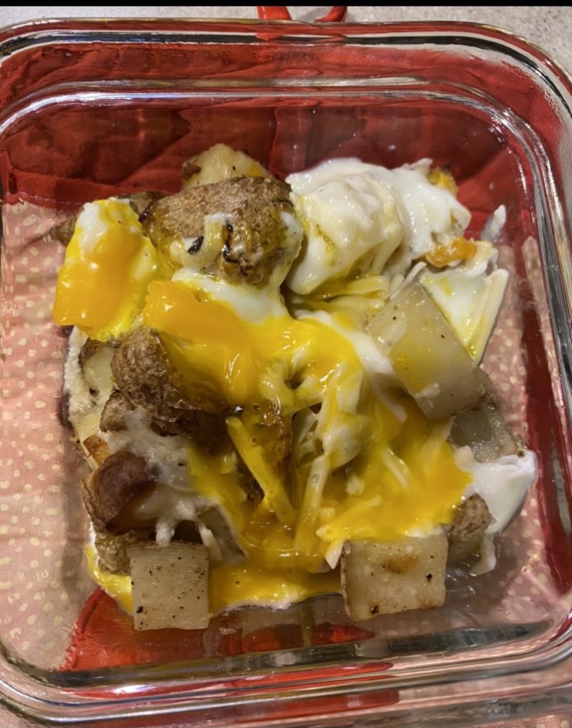 Egg cracked open on top of potato dish