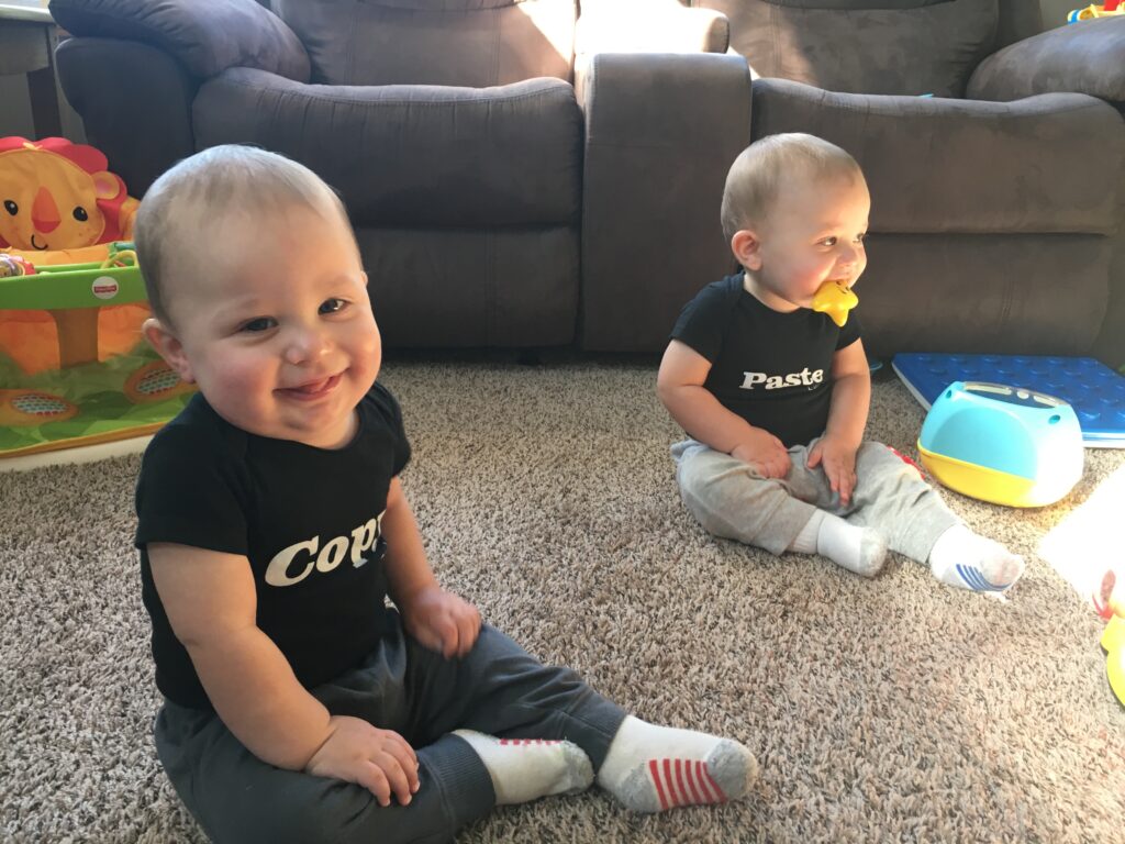 Twins sitting and looking all cute in their Copy and Paste onesies!