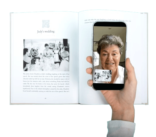 Remento preserves family memories forever. This image shows an example of a hardcover book created by Remento, based on the information provided by the mom of the family. A person is holding a phone, showing that they scanned the QR code on the page to see the mom talking about her wedding, which then is in text on the book.